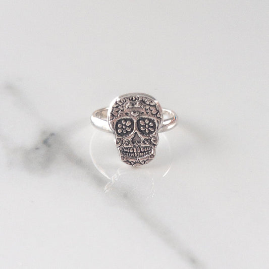 Sterling silver sugar skull ring with fine detailing, displayed on neutral background — Catholic memento mori jewelry for All Souls’ Day and reflection.