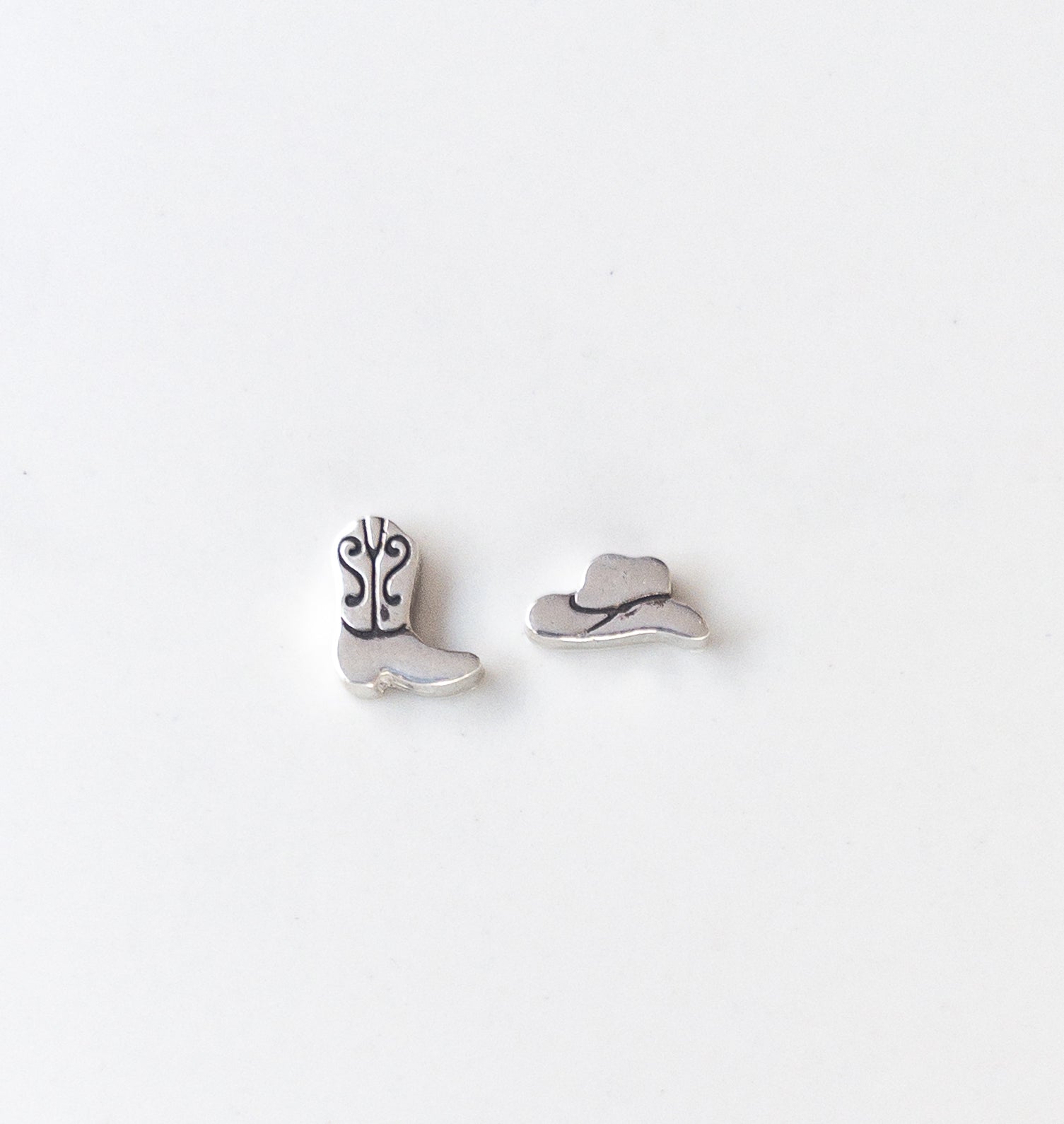 Sterling silver mismatched cowboy hat and boot stud earrings with polished finish, displayed on neutral background – Western jewelry gift for her.