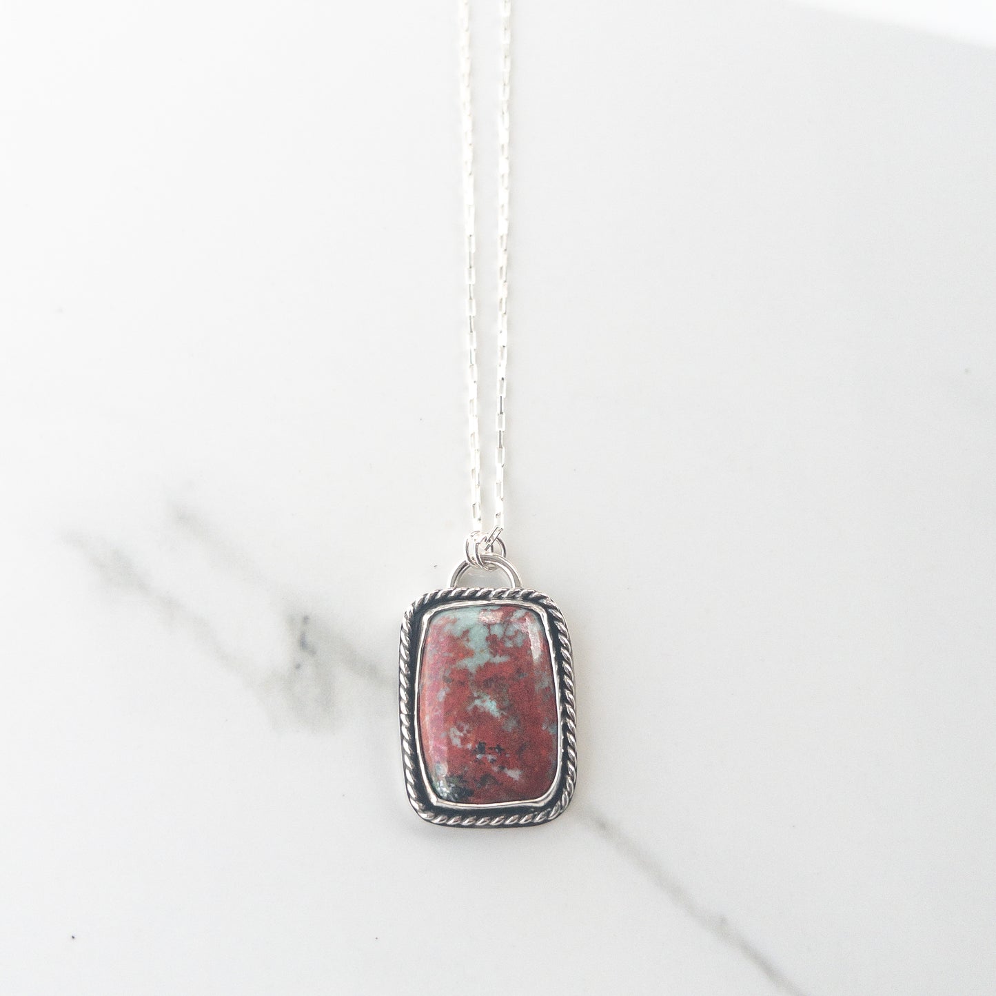 Sonoran Sunrise gemstone necklace in sterling silver with twisted wire bezel and crucifix cutout back, displayed on neutral fabric – Catholic statement jewelry
