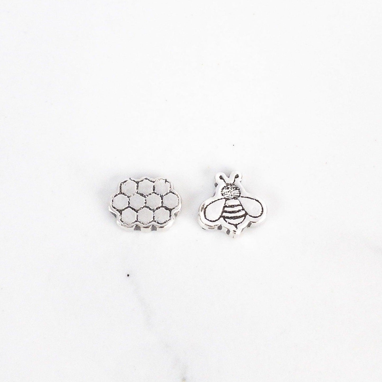 Sagely Sparrow Bee and Honeycomb Stud Earrings on a white background. Honeycomb on left and bee on right.