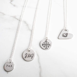 Sagely Sparrow Sterling Silver Necklaces (Pax, JMJ, Jerusalem Cross, and Sacred Heart) in a line on a white background with black and gray marbling