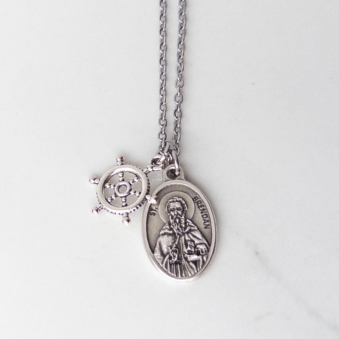 St. Brendan saint medal necklace with a ship's wheel charm on a stainless steel chain