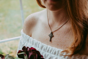 Sagely Sparrow cross necklace on a woman with red hair holding flowers