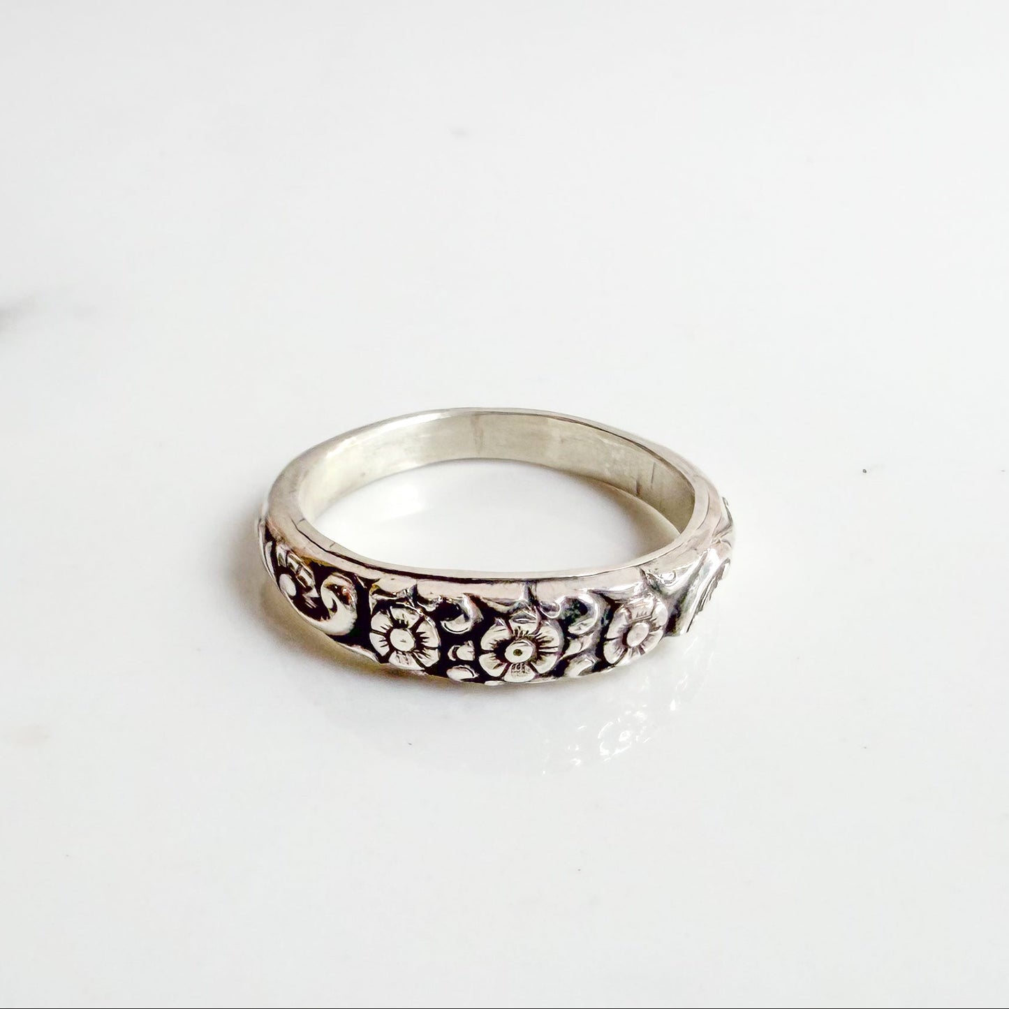 Sterling silver ring with three daisy flowers, inspired by the Little Flower, shown on neutral background – Catholic floral jewelry for women.