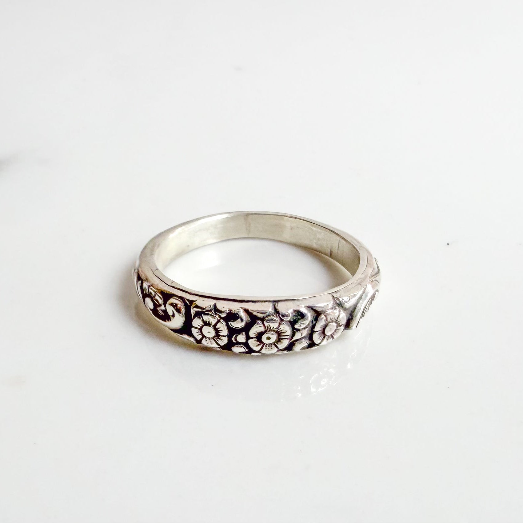 Sterling silver ring with three daisy flowers, inspired by the Little Flower, shown on neutral background – Catholic floral jewelry for women.