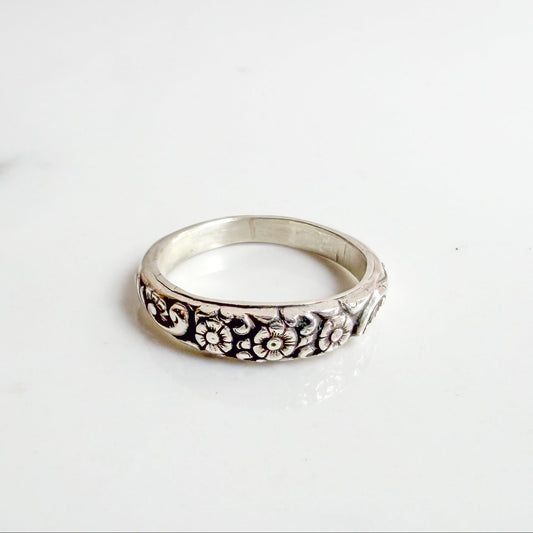 Sterling silver ring with three daisy flowers, inspired by the Little Flower, shown on neutral background – Catholic floral jewelry for women.