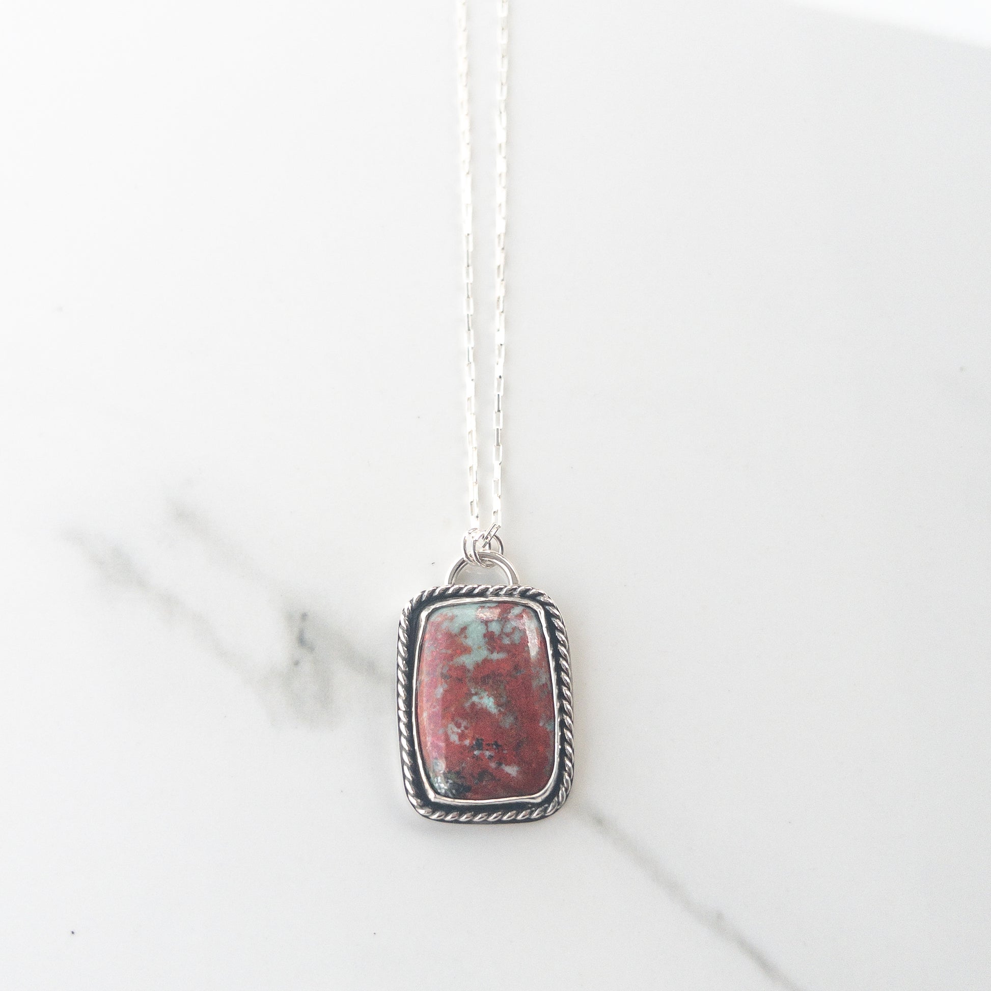 Sonoran Sunrise gemstone necklace in sterling silver with twisted wire bezel and crucifix cutout back, displayed on neutral fabric – Catholic statement jewelry