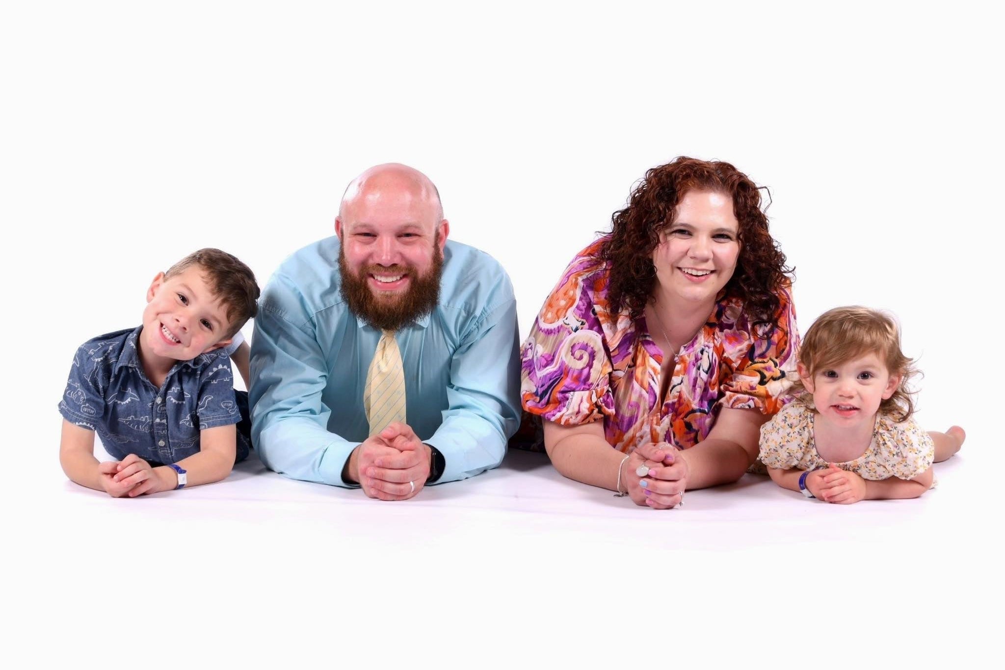 Family of four posing together on a white background