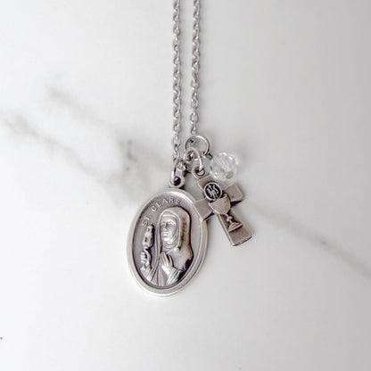St. Clare of Assisi necklace with oval saint medal, silver-tone chalice and Eucharistic host IHS charm, and clear glass bead on stainless steel chain – Catholic Confirmation gift for girls.