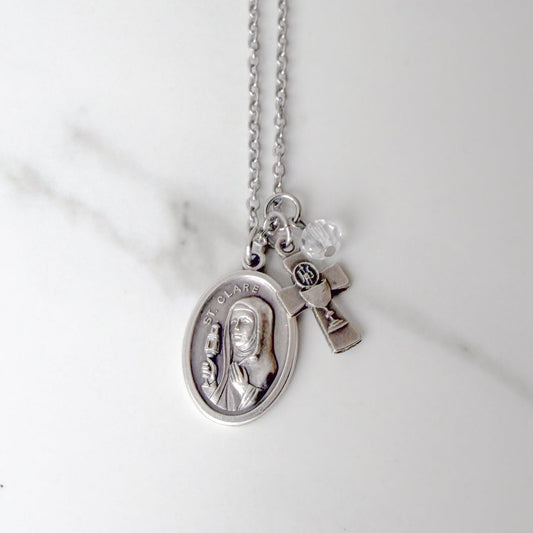 St. Clare of Assisi necklace with oval saint medal, silver-tone chalice and Eucharistic host IHS charm, and clear glass bead on stainless steel chain – Catholic Confirmation gift for girls.