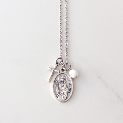 St. Agnes necklace with Italian medal, crucifix charm, and white bead on stainless steel chain, displayed on soft neutral background – Catholic jewelry for girls.