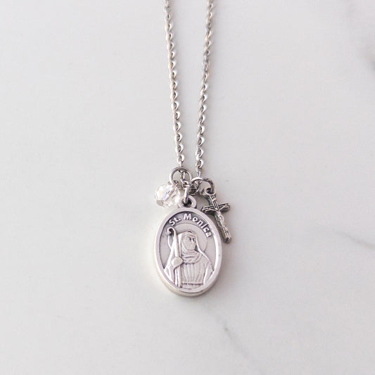 St. Monica and crucifix necklace with clear glass bead on stainless steel chain, displayed on neutral background – Catholic jewelry gift for mothers or Confirmation