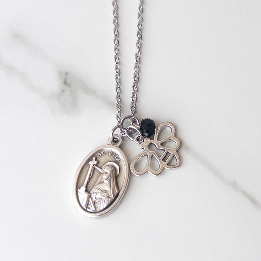 St. Rita of Cascia necklace with silver medal, bee charm, and black accent bead on stainless steel chain, displayed on neutral background – Catholic jewelry for Confirmation and encouragement gift