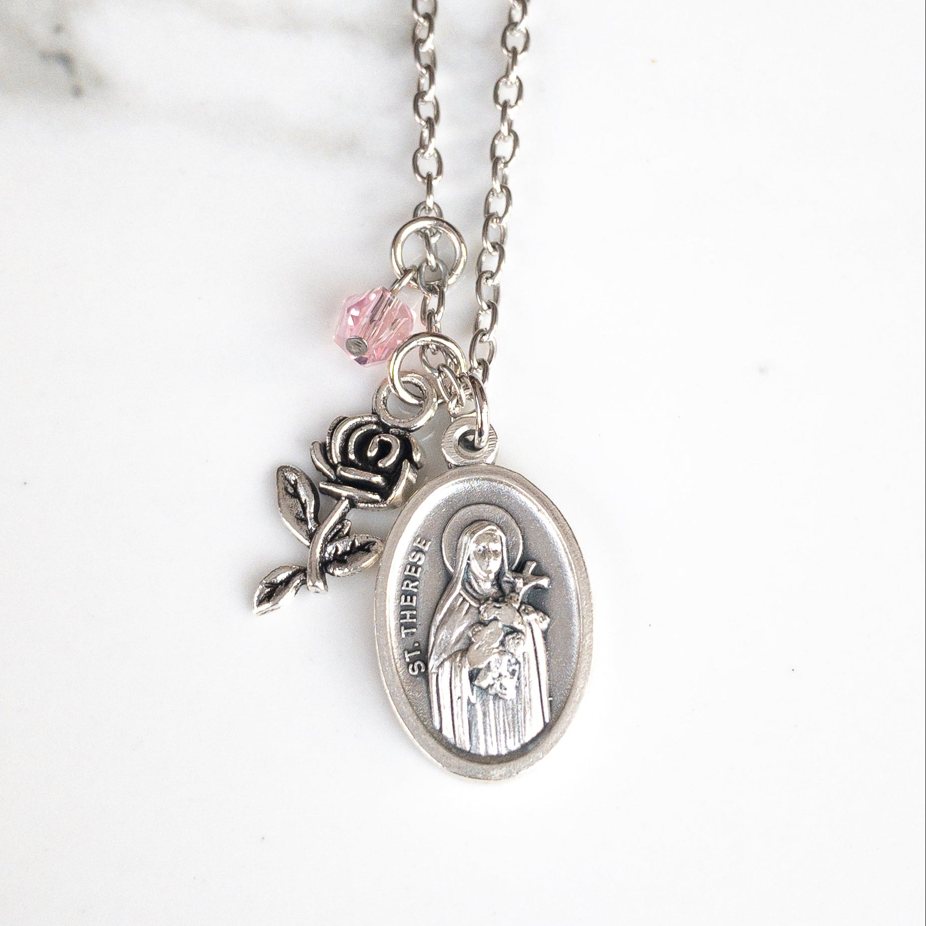 St Therese of Lisieux Confirmation patron saint necklace, featuring St Therese medal, silver tone rose charm, and small pink bead, all on a stainless steel chain. 