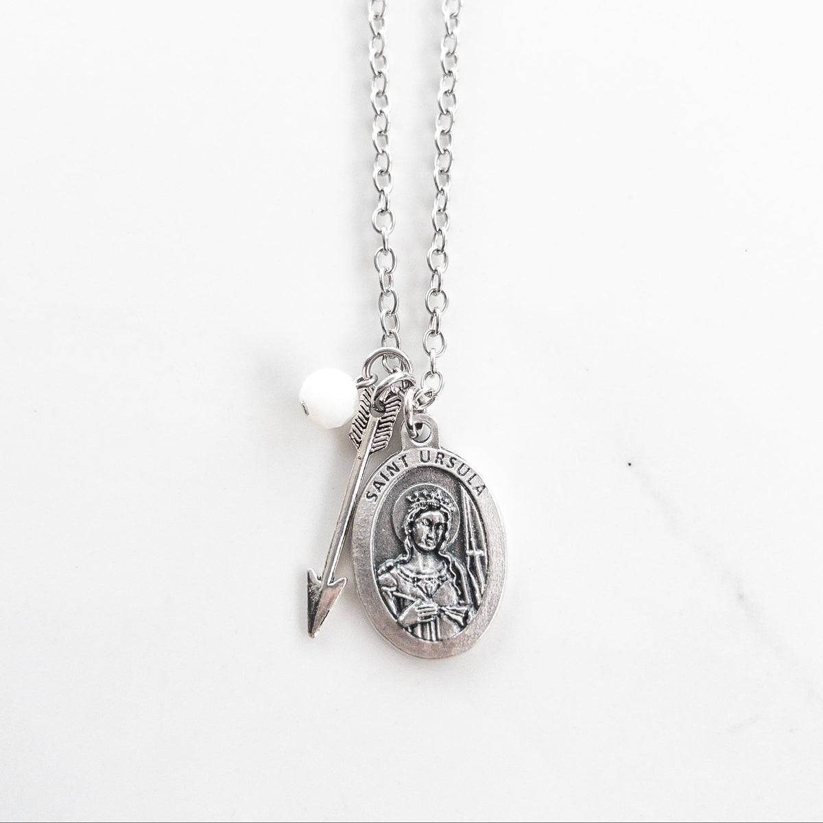 Saint Ursula medal necklace with silver arrow charm and white glass bead on a stainless steel chain