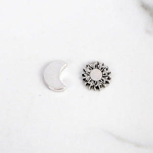 Sagely Sparrow Sun and Moon Stud Earrings Flat on a white background. Smooth crescent moon shape on left and textured sun shape on right.